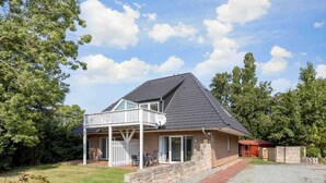 A two-story house with a balcony, a stone wall, and a gravel driveway. - Apartment 1 Küstenkind (ID 391) (Sankt Peter-Ording)