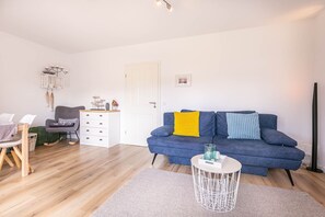 Un salon moderne avec un canapé bleu, une table basse blanche et un tapis gris.