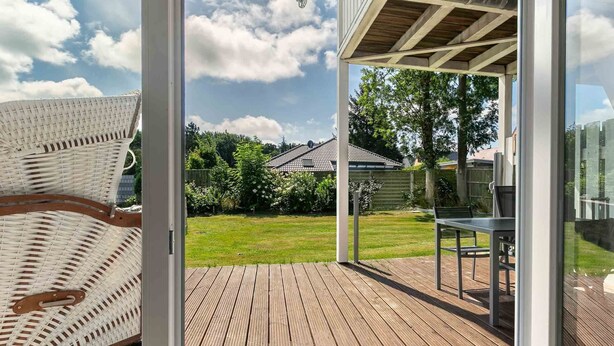 A wooden deck with a glass door leading to a backyard. - Apartment 1 Küstenkind (ID 391) (Sankt Peter-Ording)