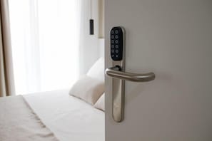 Et moderne hotelværelse med en elektronisk dør låst fast på væggen og en seng med hvide sengetøj.