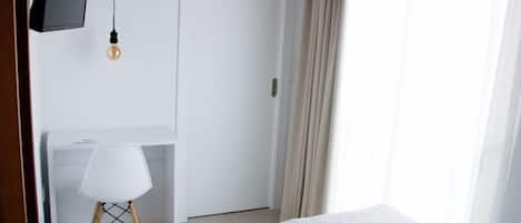 Un dormitorio con cama, escritorio, silla y televisor.
