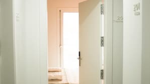 Ein Flur, der zu einem Zimmer mit einem Bett und einer Tür mit der Aufschrift '301' führt.