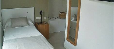 A modern bedroom with a large bed, bedside table, and a mirror.