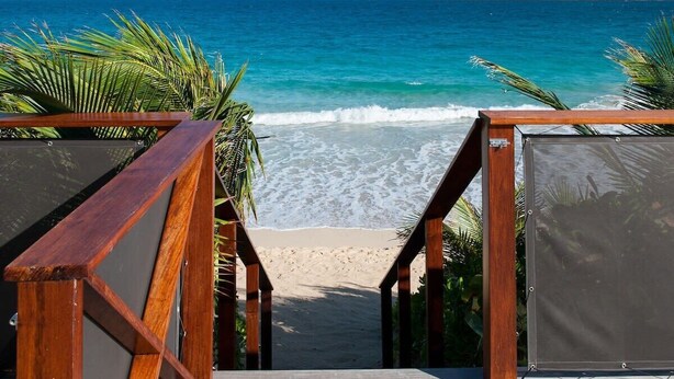 A wooden staircase leading to a beach with clear turquoise water and a distant island. - Villa MICELA – Beachfront Escape with Pool in Flamands, St. Barths (Gustavia)
