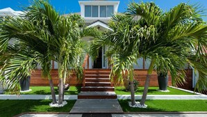 A modern house with a wooden facade, a central staircase, and palm trees in the front yard. - Villa MICELA – Beachfront Escape with Pool in Flamands, St. Barths (Gustavia)