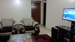 En stue med sofa, sofabord, fjernsyn og ventilator.