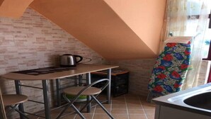 A small kitchenette with a tiled floor, a table with chairs, a kettle, and a colorful ironing board. - Beautiful house - fiumefreddo (fiumofreddo)