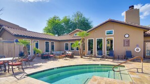 Ein Poolbereich mit Terrasse, Liegestühlen und einer überdachten Sitzgruppe.