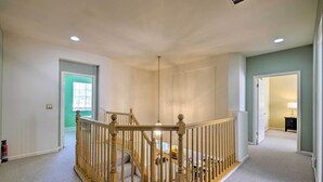 A spacious hallway with a wooden staircase, a fire extinguisher, and a door leading to another room. - Family-Friendly Tracy House with Patio & Grill! (Tracy)