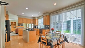 A spacious kitchen with wooden cabinets, a central island, and a dining area with a glass table and chairs. - Family-Friendly Tracy House with Patio & Grill! (Tracy)