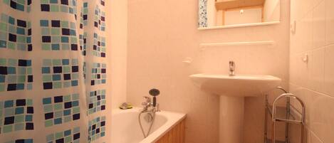 A bathroom with a white sink, a wooden bathtub, and a shower curtain with a blue and white pattern.