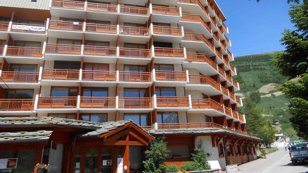 A multi-story hotel with balconies, a ski resort in the background, and a clear blue sky. - Studio for 4, ski-in ski-out, Les Deux Alpes (Les Deux Alpes)