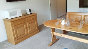 A room with a wooden cabinet, a microwave, a coffee maker, and a dining table with several clear glasses and a white pitcher. - Studio for 4, ski-in ski-out, Les Deux Alpes (Les Deux Alpes)