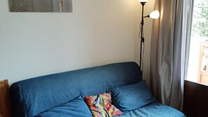 A blue sofa with a colorful pillow, a floor lamp, and a window with curtains. - Studio for 4, ski-in ski-out, Les Deux Alpes (Les Deux Alpes)