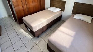 Ein Schlafzimmer mit zwei Betten, einem Holzschrank und einem Deckenventilator.