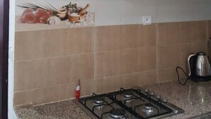 Une cuisine équipée d’une cuisinière à gaz, de meubles blancs et d’un chauffe-eau.