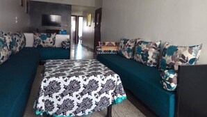 Un salon comprenant un canapé, un plaid à motifs et un tableau accroché au mur.