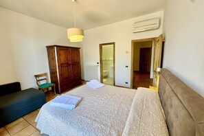 Una camera da letto con un letto, un armadio in legno, una sedia e un termosifone.