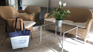 Un rincón con mobiliario de mimbre, una mesa de vidrio y una planta en maceta.