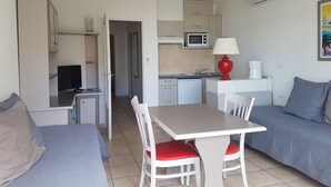 Un espacio habitable compacto con kitchenette, zona de comedor y área de descanso con sofá y mesa.