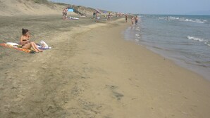 Une plage de sable où des gens se prélassent au soleil et se baignent.