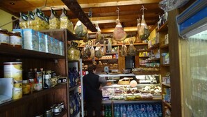 Une petite épicerie avec des étagères en bois remplies de conserves, de pâtes et d’autres produits alimentaires.