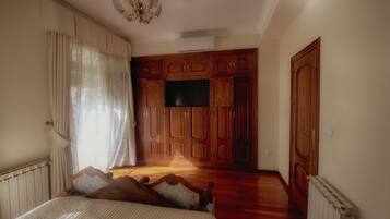 Un dormitorio con cama, armario de madera y televisor en la pared.