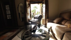 Un salon avec une table basse en verre, un canapé en cuir et une fenêtre avec des stores.