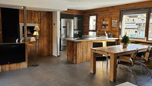 Una cucina moderna con elementi in legno, elettrodomestici in acciaio inossidabile e un'area pranzo con tavolo e sedie di legno.