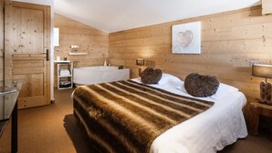 Una camera da letto con un letto grande, una parete in legno, una vasca da bagno e una porta di legno.