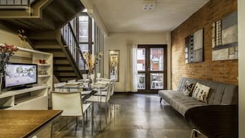 Un espacio habitable moderno con escalera, comedor y sofá.