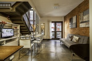 A modern living space with a staircase, dining area, and a sofa.