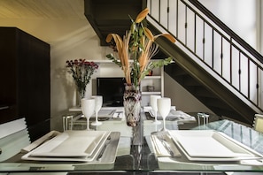 A dining table set with white plates, cutlery, and glasses, with a decorative vase in the center. - IMPERDIBLE PROMOTION PREMIUM LOFT IN RECOLETA!!! ⭐⭐⭐⭐⭐ (Ciudad Autónoma de Buenos Aires, Recolet)
