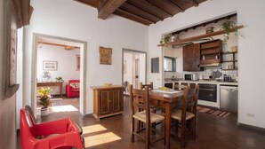 A kitchen with wooden cabinets, a microwave, and a dishwasher. There is a dining area with a wooden table and chairs. - Spacious and charming apartment in the heart of Florence (Firenze, Italia)