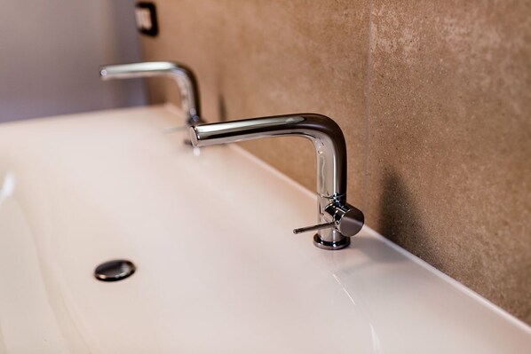Un baño moderno con un lavabo blanco, grifos cromados y una pared color crema.