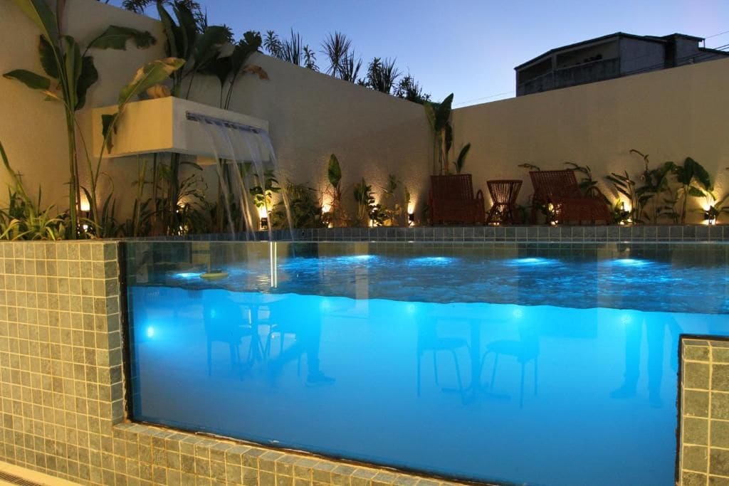 A swimming pool with chairs and plants around it.