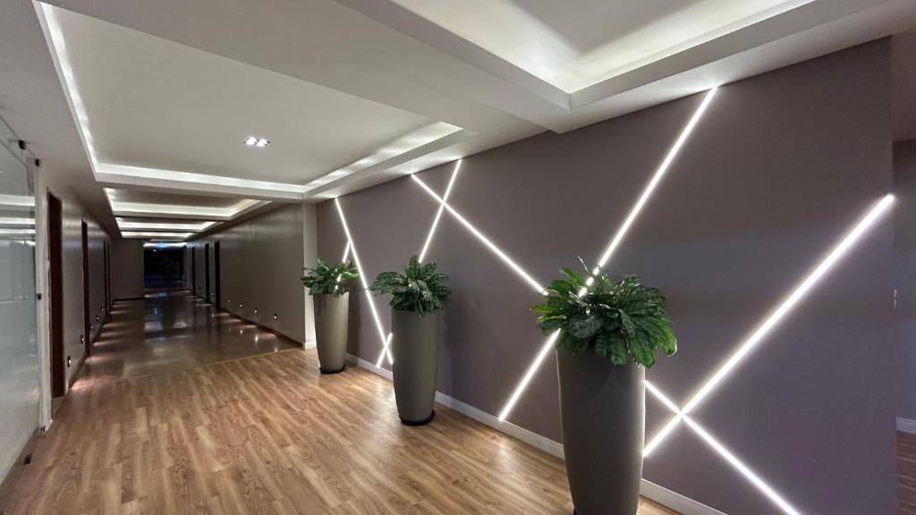 Un couloir moderne avec un plancher en bois, des plantes en pot et des motifs géométriques lumineux sur les murs.