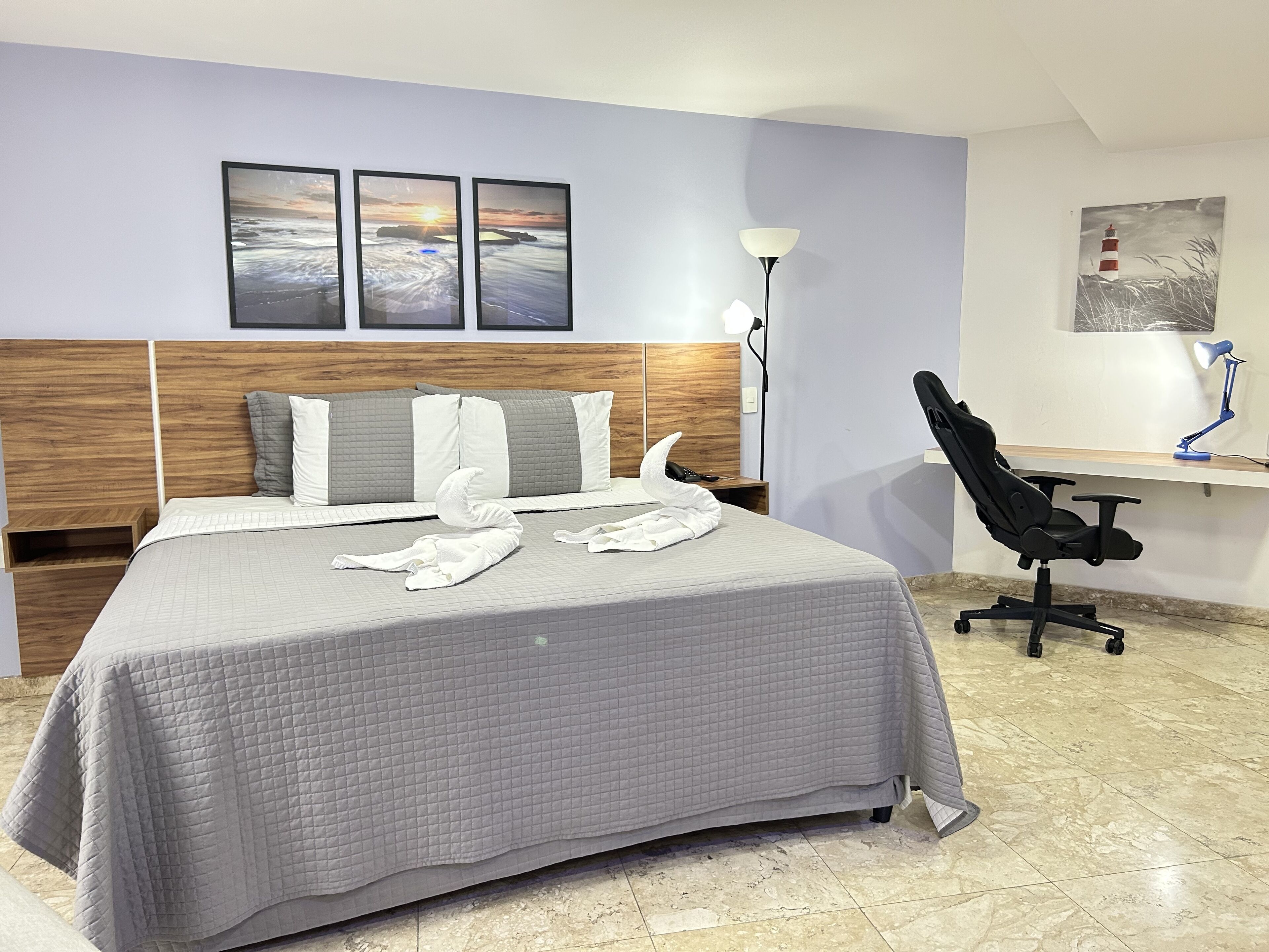 Een hotelkamer met een bed, een bureau, een stoel en kunstwerken aan de muur.