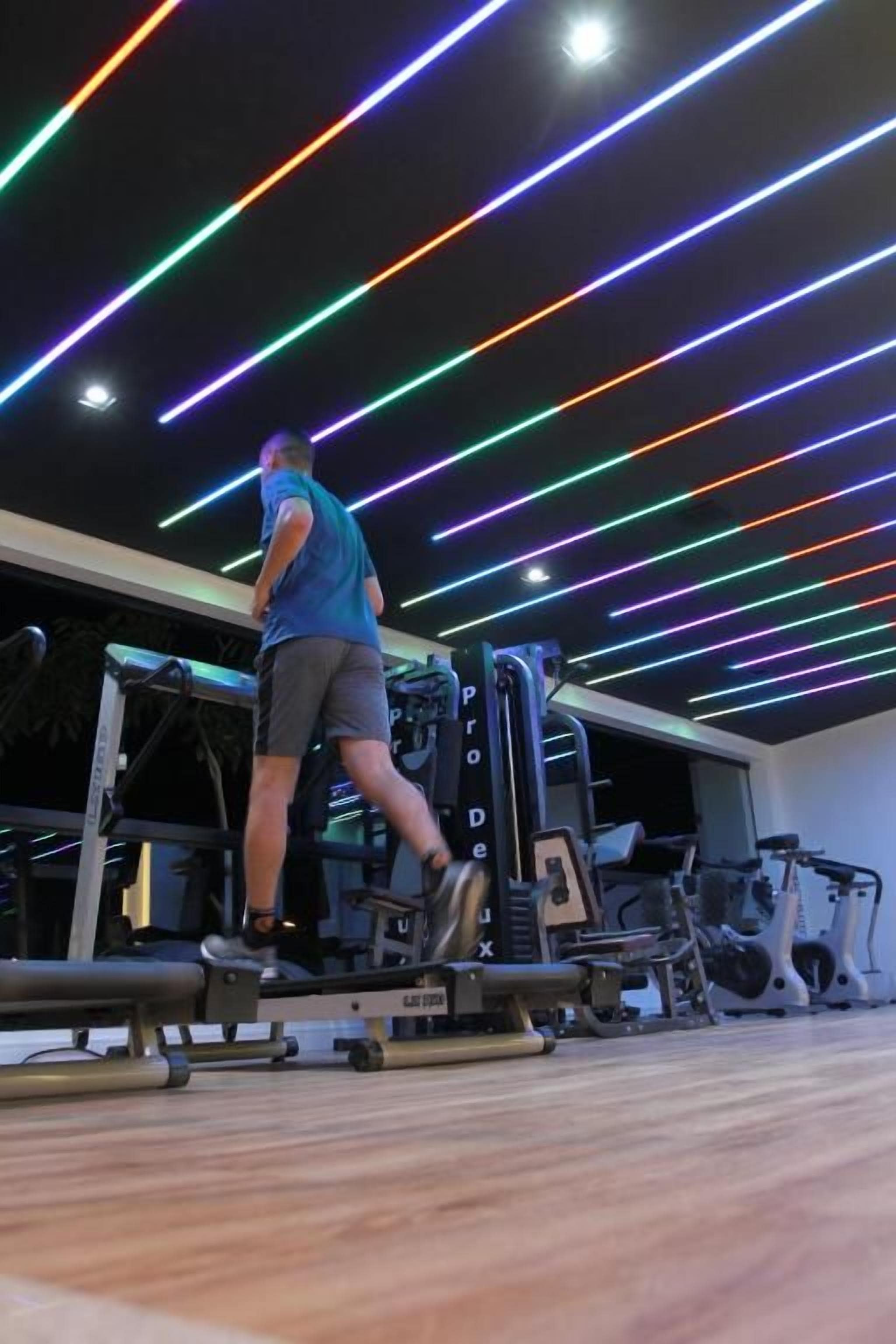 Een persoon gebruikt een bekniebuigapparaat in een sportschool, met een plafond met lineaire LED-verlichting.