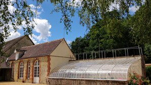 A building with a greenhouse structure attached to the side. - the Grand Potager, a very beautiful calm and preserved environment (Mittainvilliers-Vérigny)