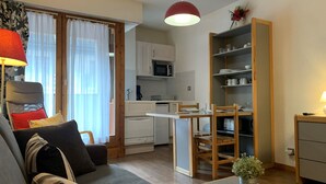Un espacio habitable compacto con sofá, mesa de comedor y kitchenette.