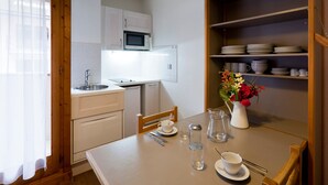 Una cocina compacta con armarios blancos, un microondas y una mesa de comedor decorada con un jarrón de flores.