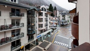 Un hotel con varios pisos, balcones y vista a una montaña nevada.