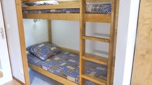 A bunk bed with a wooden frame and patterned bedding. - Central studio in Brides-les-Bains with balcony and WiFi (Brides-les-Bains)