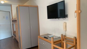 Un dormitorio con literas, un escritorio con silla, una televisión y un teléfono.