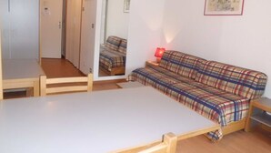 A compact room with a bed, a wooden table, a red lamp, and a mirror. - Studio 4 Pers, Center Brides-les-Bains, Wifi, Parking (Brides-les-Bains)
