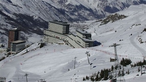 A hotel with multiple floors, ski slopes, and a mountainous backdrop.