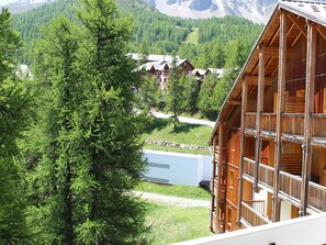 A wooden chalet with multiple balconies, surrounded by lush greenery and mountains in the background. - Cozy studio 27m², sleeps 4, 200m from slopes in Vars (Vars)