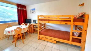 Un lit superposé avec un bureau et une chaise, un ordinateur portable et une fenêtre donnant sur un beau paysage.