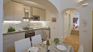 A modern kitchen with white cabinets, a microwave, and a dining area with a table set for two.